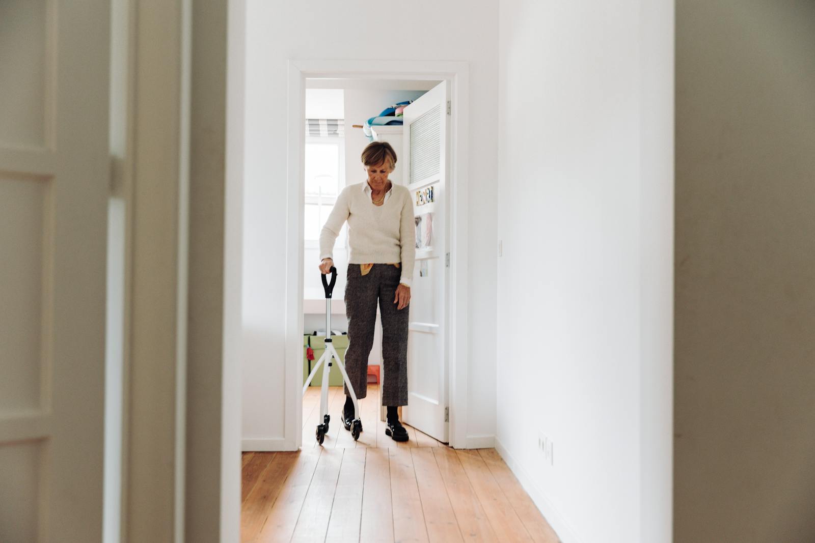 Ältere Frau bewegt sich mit Rollator sicher durch eine helle, barrierearme Wohnung