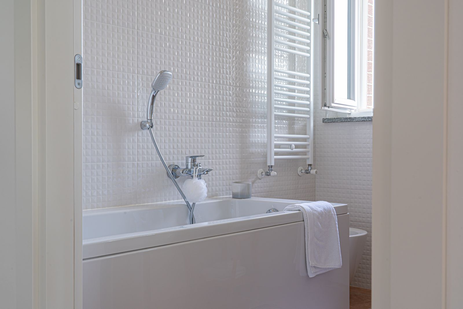 Helle Badewanne an gefliester Wand in einem modernen Bad – Ausgangssituation für den nachträglichen Einbau einer Badewannentür