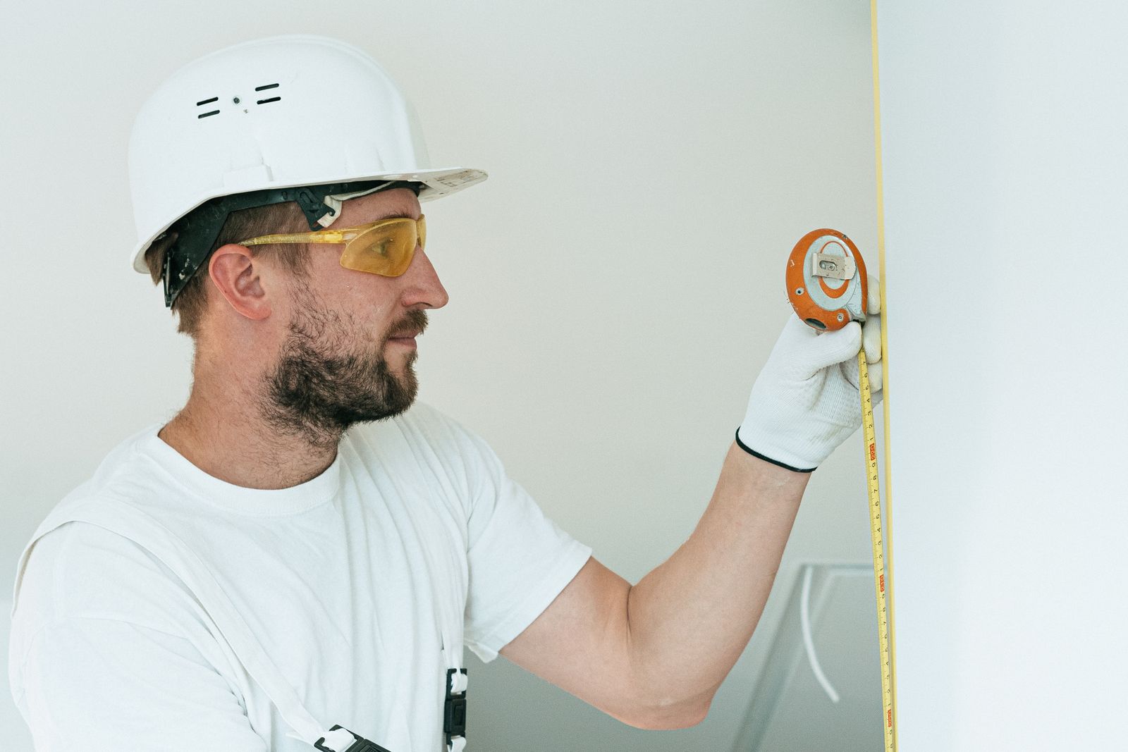 Handwerker nimmt mit dem Maßband Maß an der Wand – Aufmaß beim Badumbau