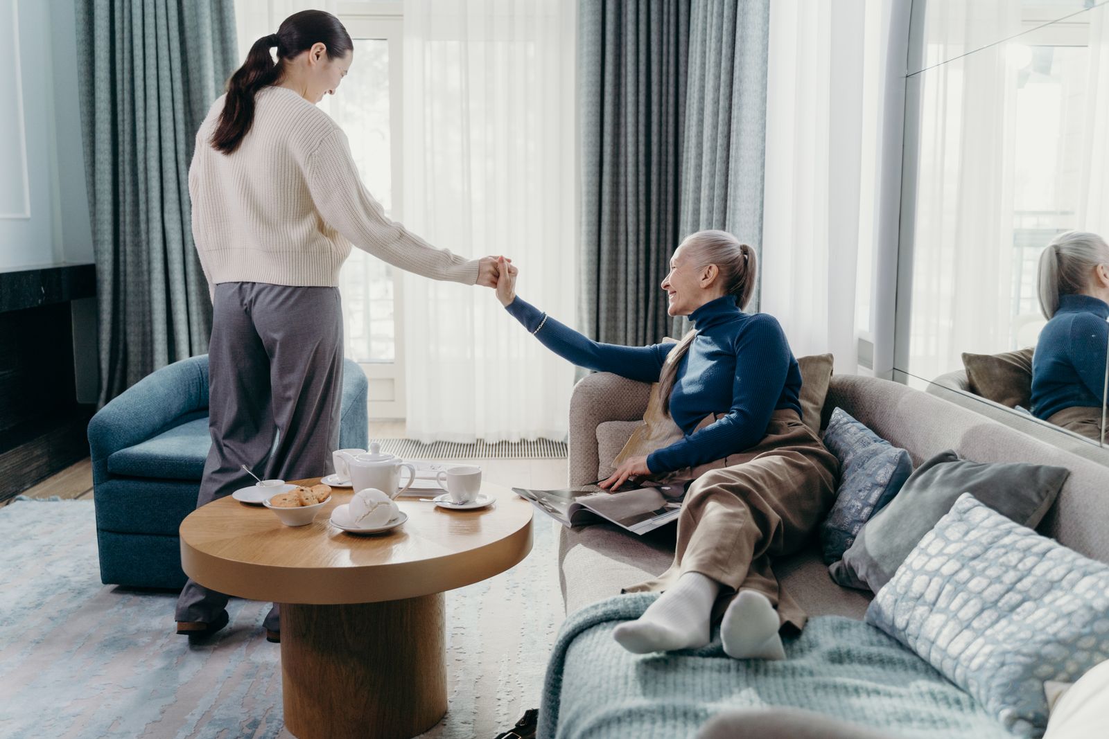 Ältere Mutter und erwachsene Tochter sitzen entspannt zusammen im Wohnzimmer