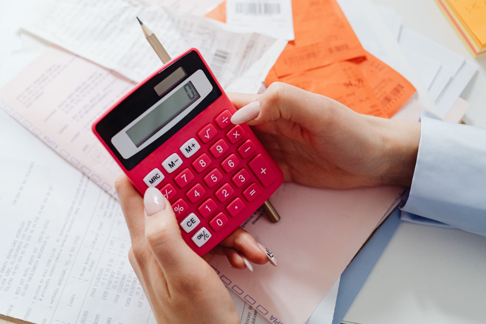 Hände mit Taschenrechner und Unterlagen bei der Finanzplanung am Tisch