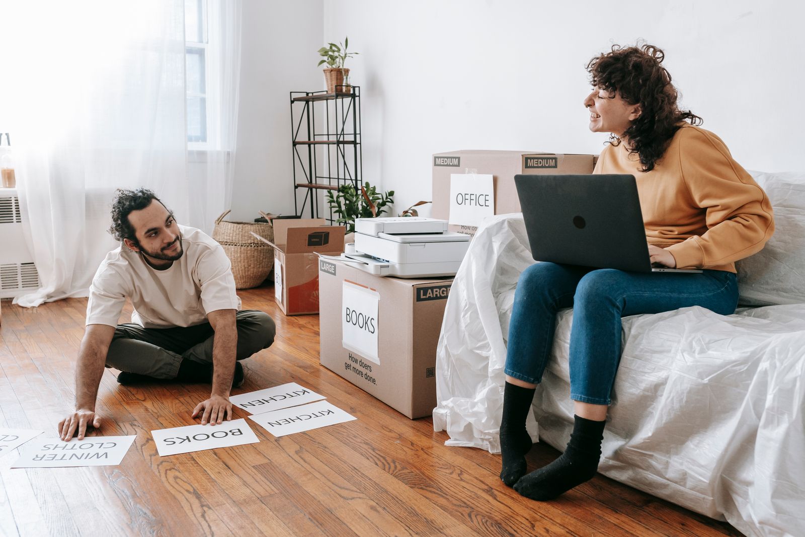Paar beschriftet gemeinsam Umzugskartons im Wohnzimmer