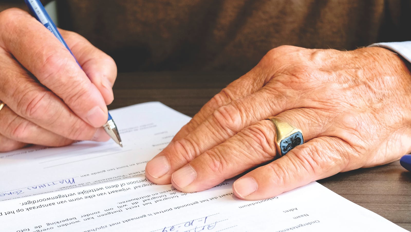 Ältere Hand unterschreibt mit einem Stift ein Vorsorge-Dokument