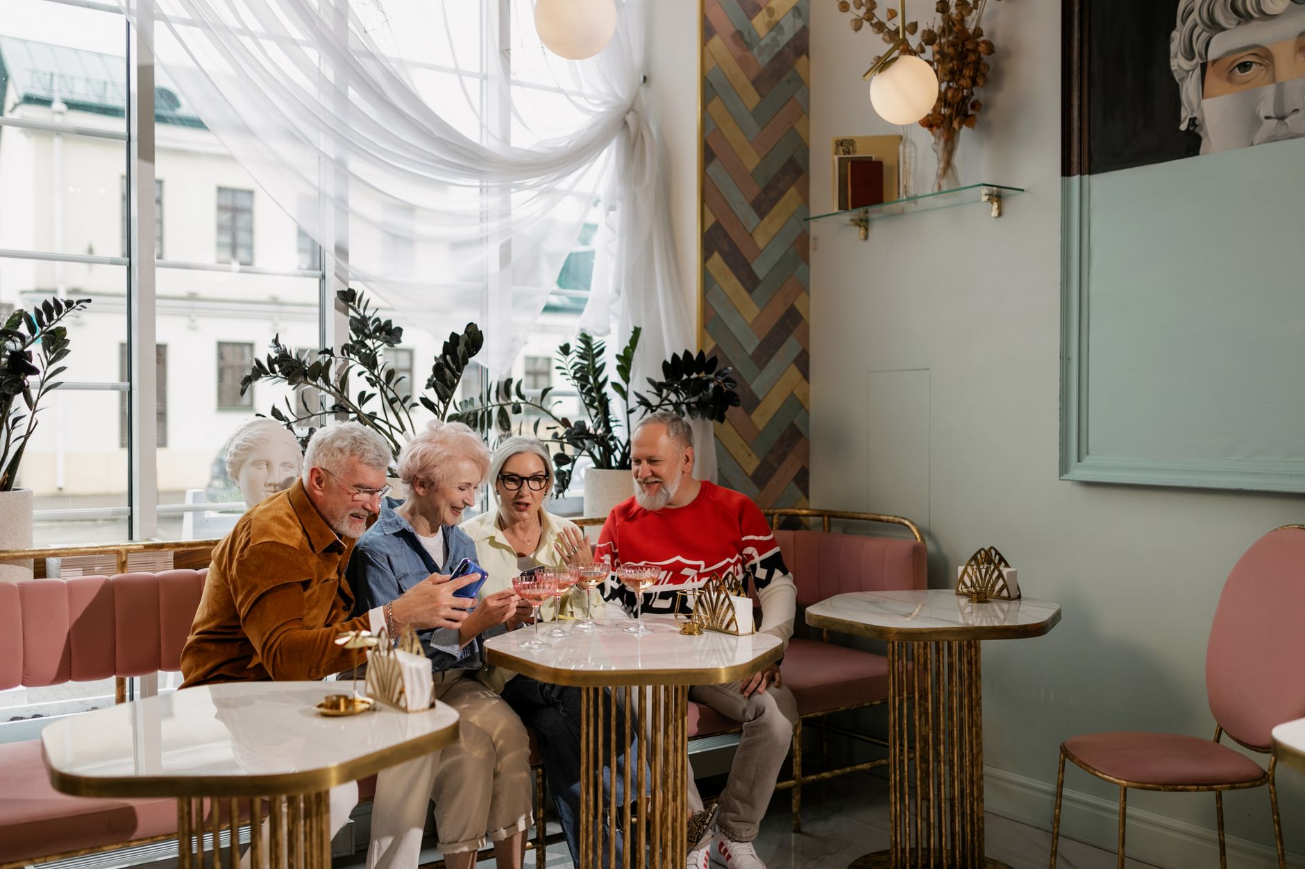 Vier ältere Menschen lachen gemeinsam bei Kaffee in einem hellen, eleganten Gemeinschaftsraum