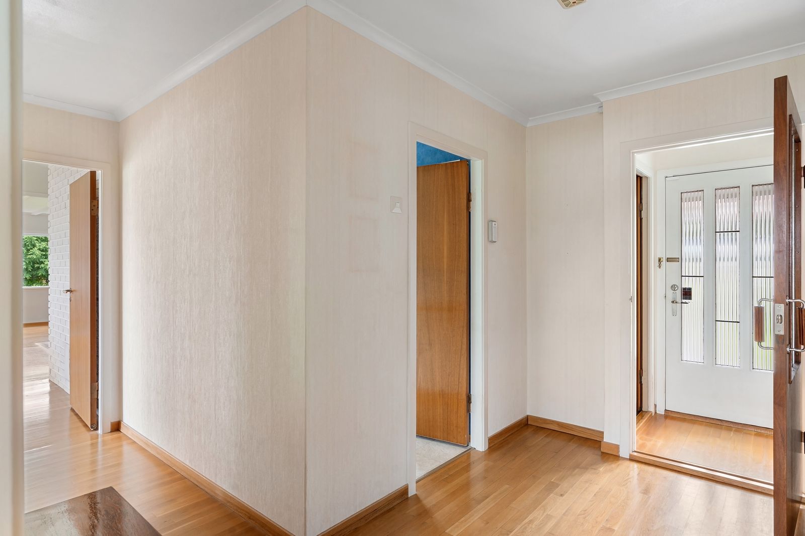 Heller Wohnflur mit offenen Türen und durchgehendem, schwellenlosem Holzboden