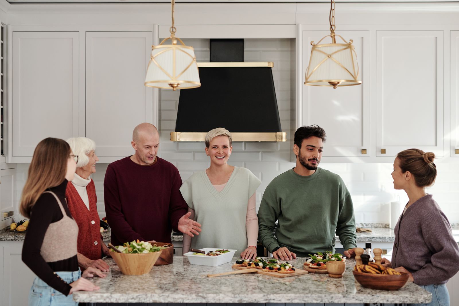Mehrere Generationen bereiten gemeinsam lachend Essen in einer Küche zu